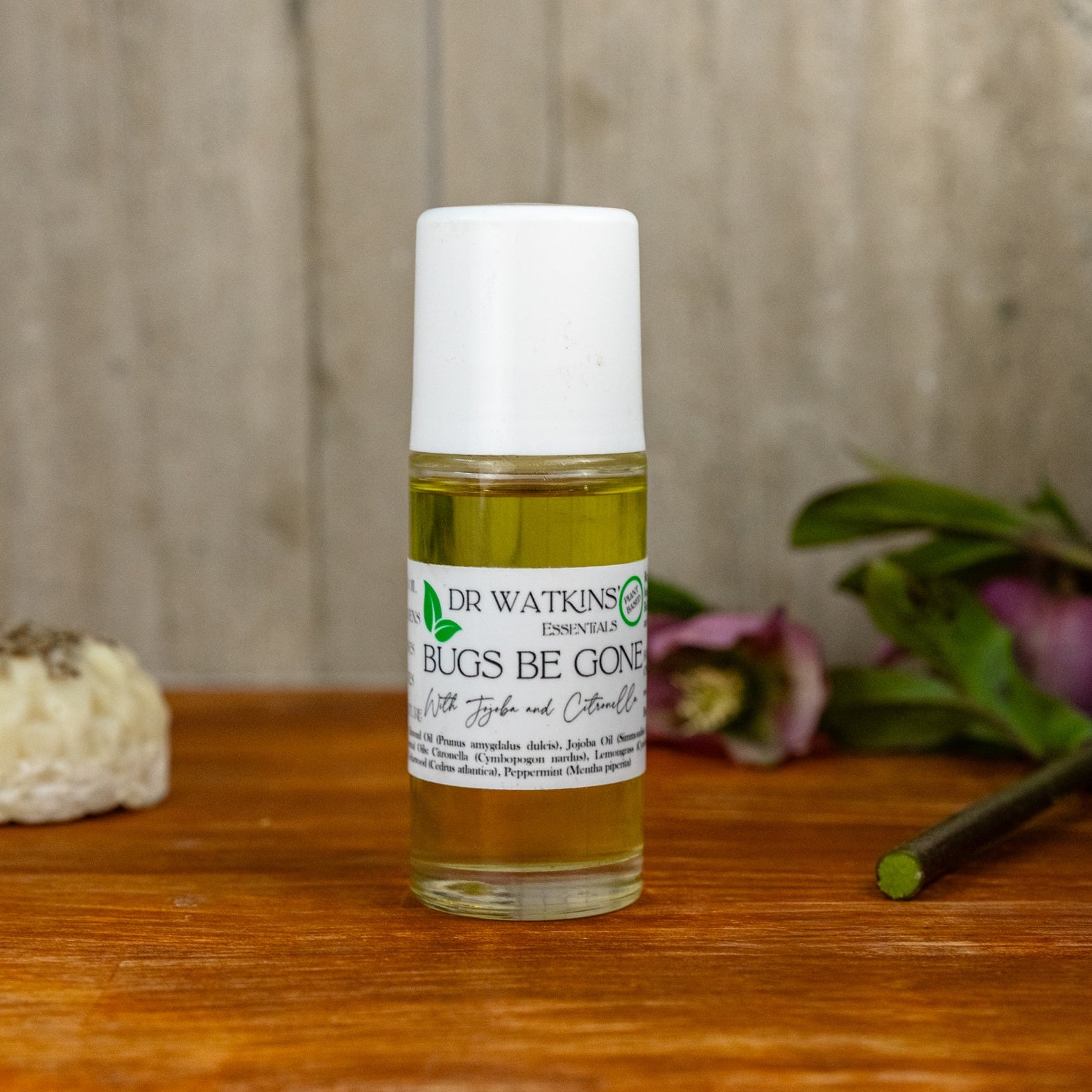Bottle of Dr. Watkins Bugs Be Gone on a wooden surface with a natural background