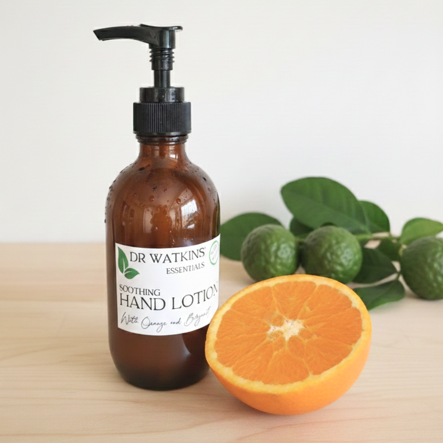 Dr. Watkins hand lotion bottle with an orange and bergamot on a wooden surface