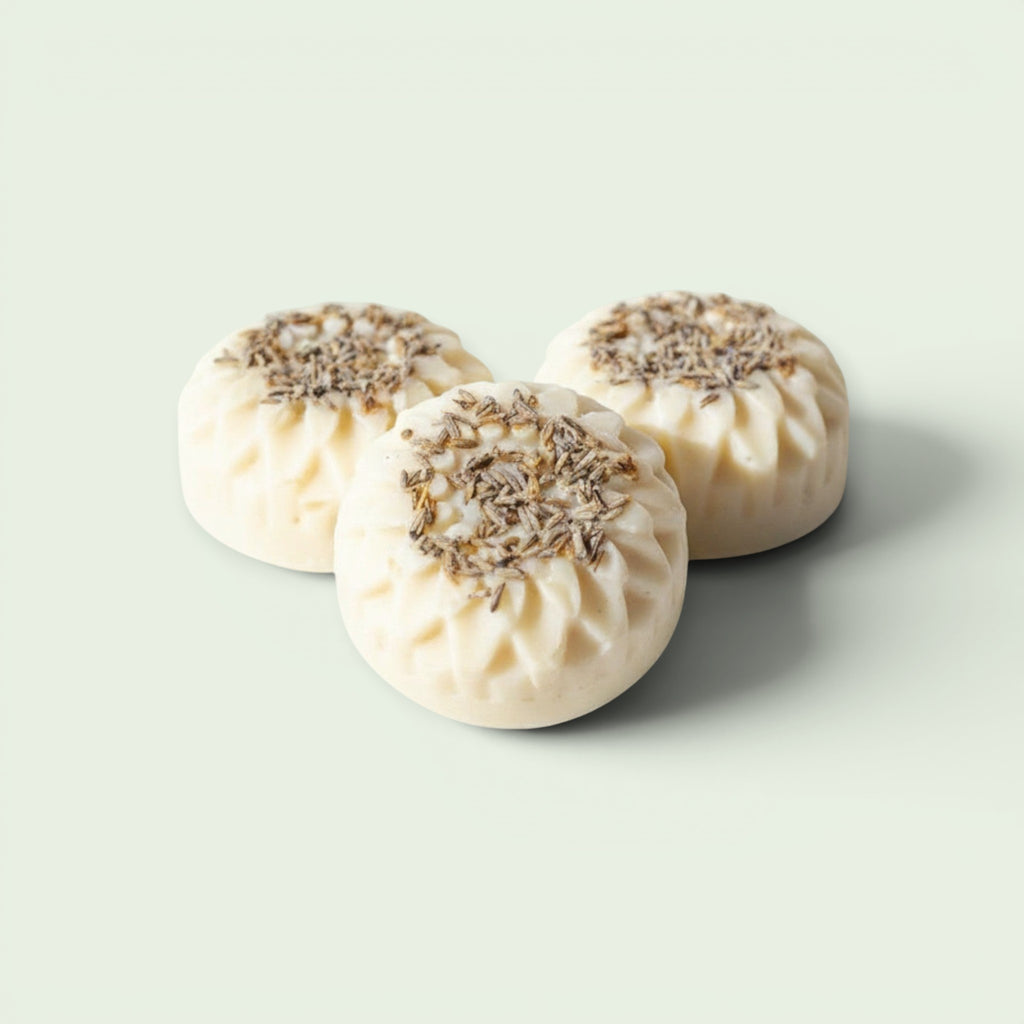 Dr Watkins Essentials three round white body creme bars with lavender buds on top, on a marble surface.