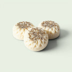 Dr Watkins Essentials three round white body creme bars with lavender buds on top, on a marble surface.