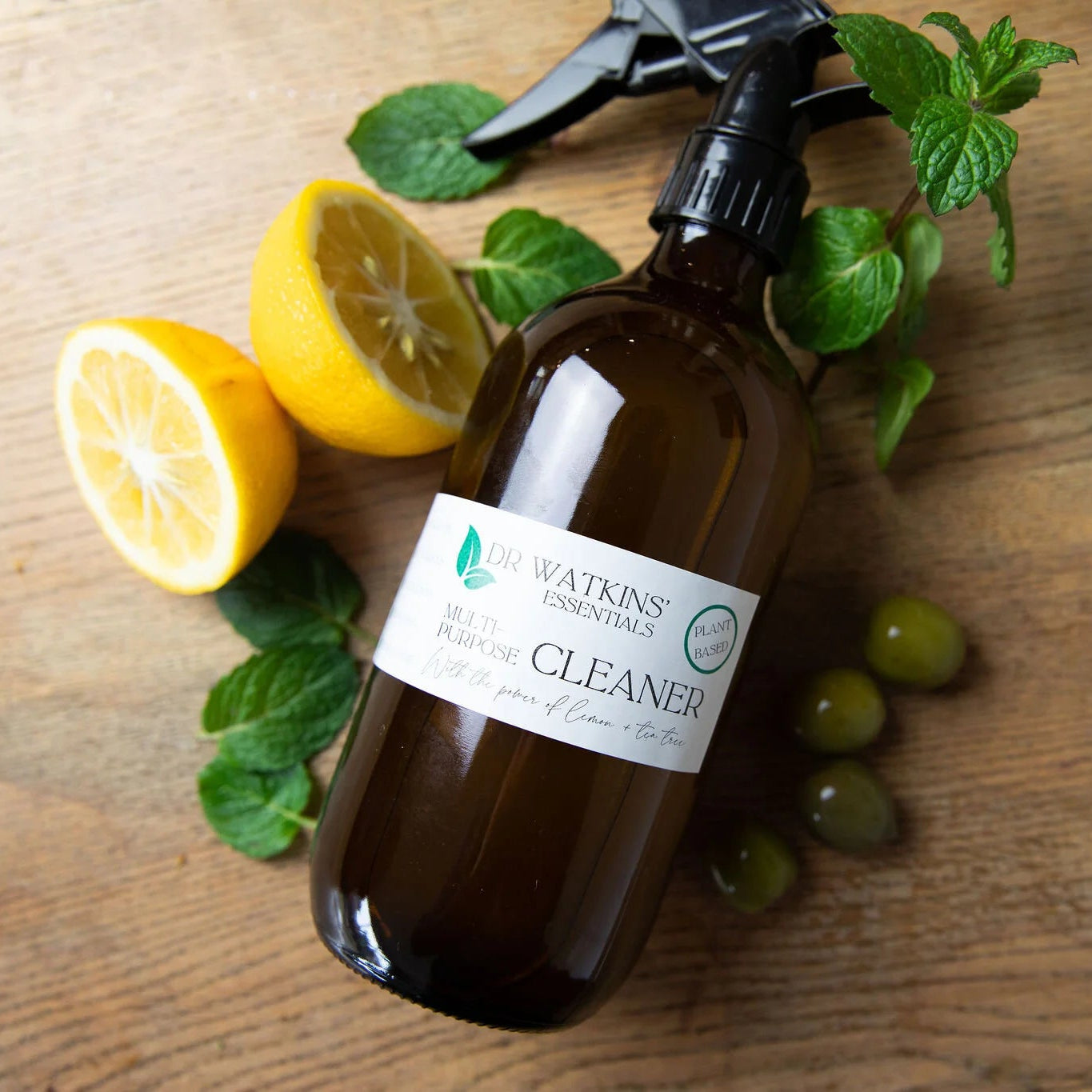 Brown spray bottle with a label on a wooden surface with lemons and mint leaves.