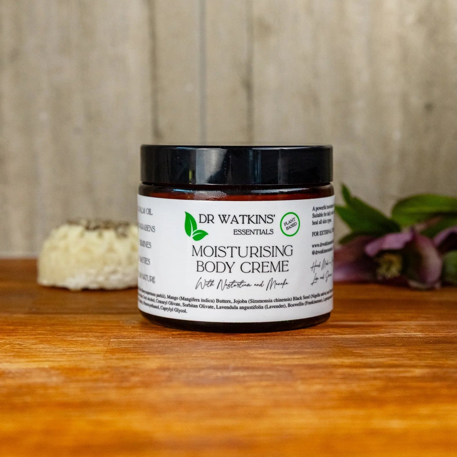 Jar of Dr. Watkins moisturizing body crème on a wooden surface with a neutral background