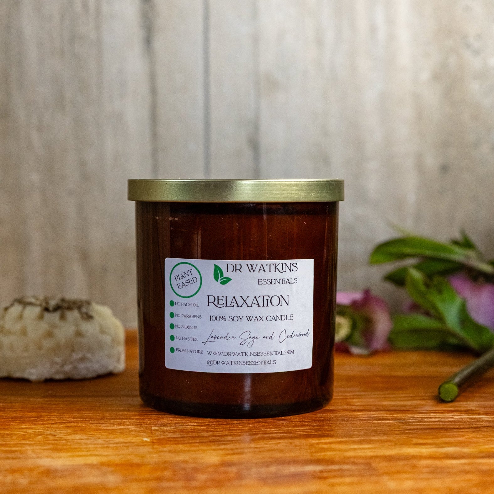 Dr. Watkins candle with a gold lid on a wooden surface with a blurred background